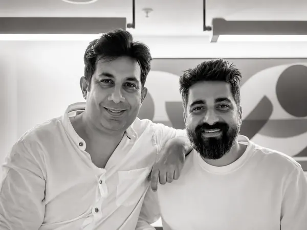 The two founders smiling together, in the original black-and-white photograph.